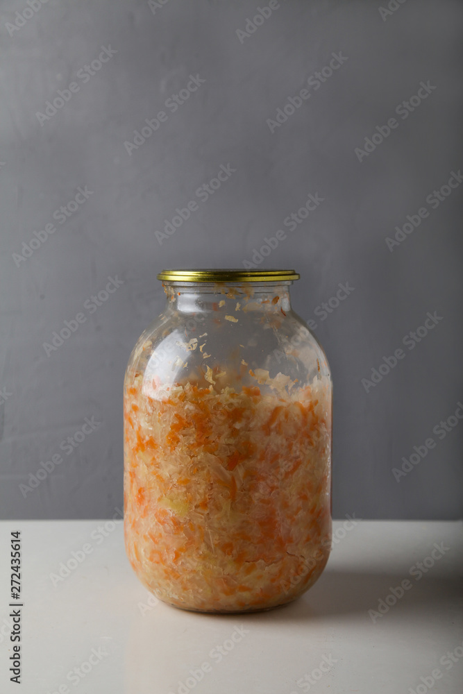 fermented cabbage in a glass jar with a lid on a gray background with copyspace
