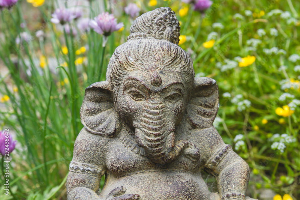 Ganesh stone statue in a garden with flowers Ganesh stone statue in a garden with flowers