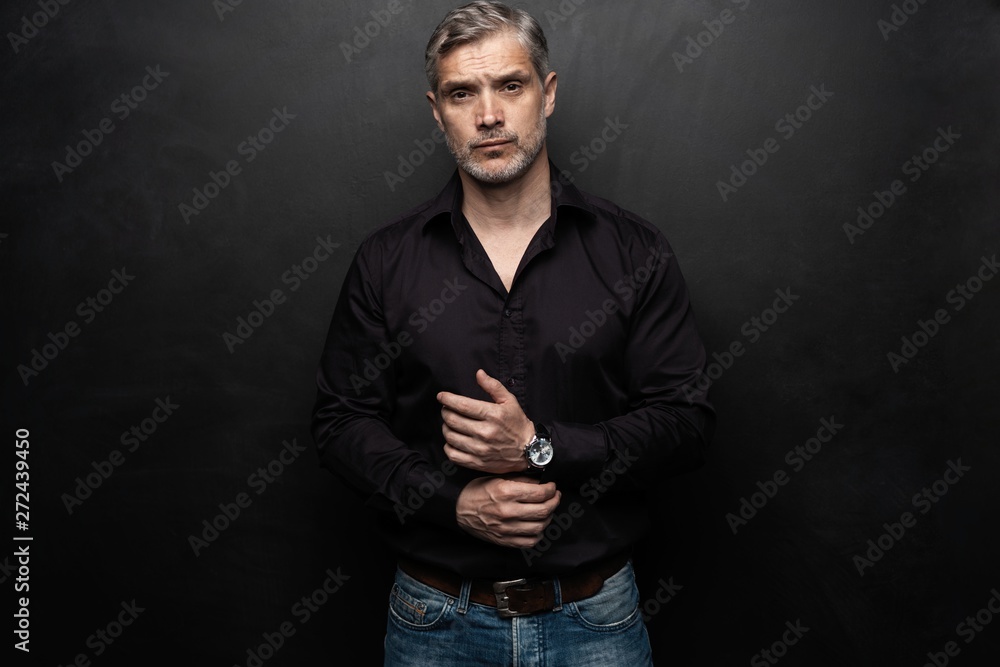 Middle-aged good looking man posing in front of a black background with copy space. Middle-aged good looking man posing in front of a black background with copy space.
