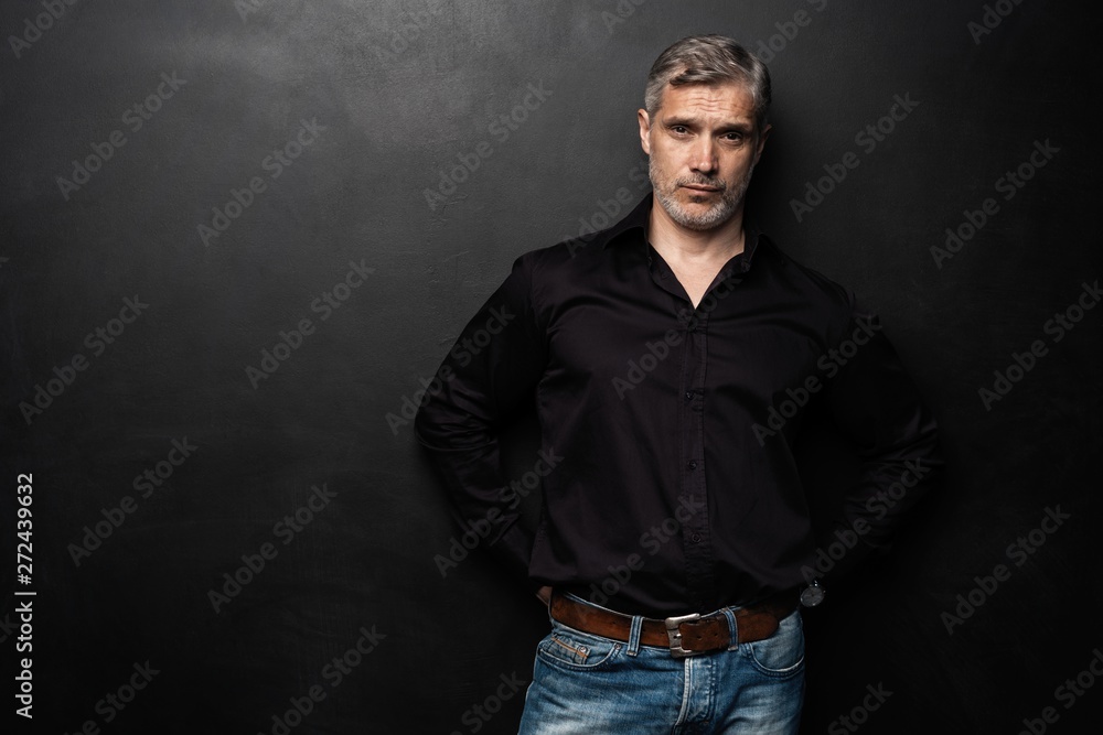 Middle-aged good looking man posing in front of a black background with copy space. Middle-aged good looking man posing in front of a black background with copy space.