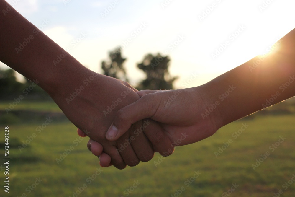 Children hold hands to show friendship, shoot blurred images, golden yellow light in the evening Children hold hands to show friendship, shoot blurred images, golden yellow light in the evening