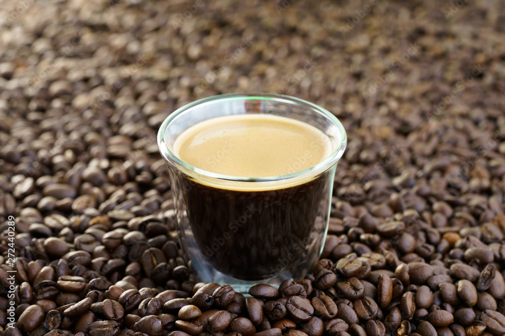 Espresso shot on a table filled with roasted coffee beans. High resolution Espresso shot on a table filled with roasted coffee beans. High resolution