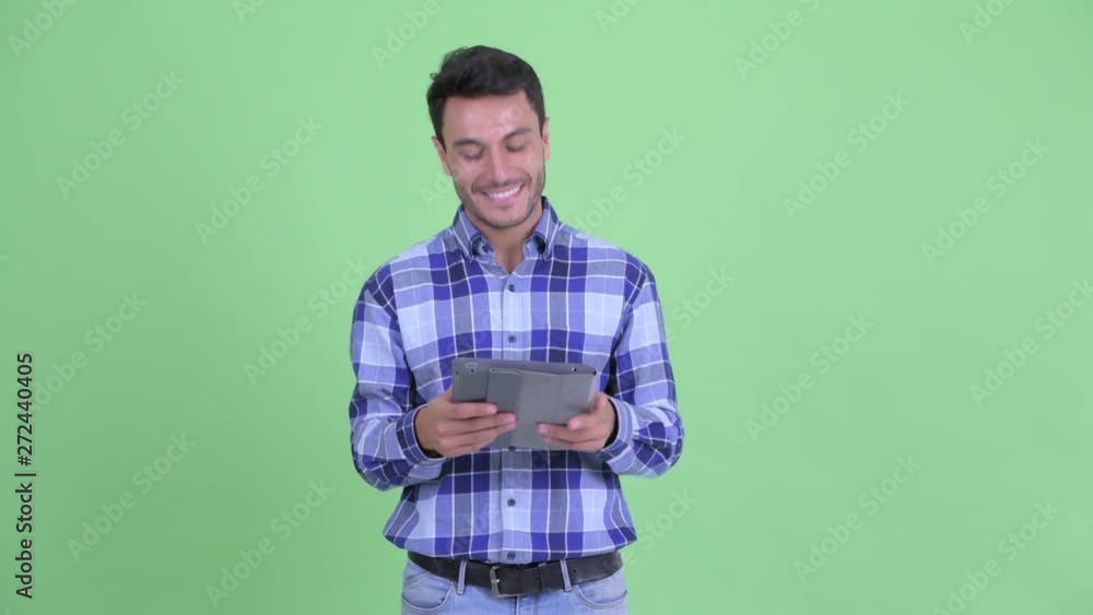Happy young Hispanic man thinking while using digital tablet Happy young Hispanic man thinking while using digital tablet