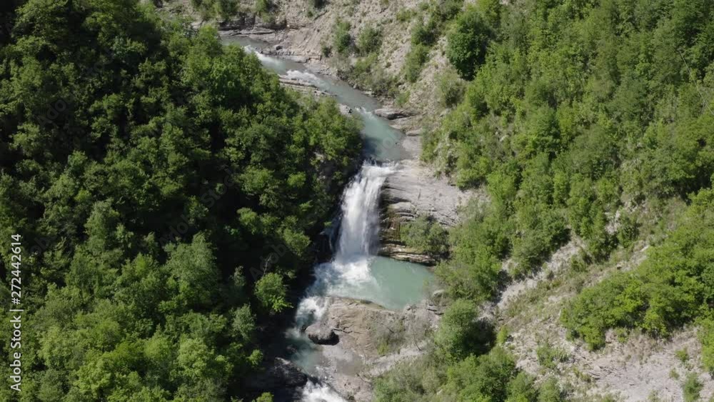 Forward drone shot of the Golfarone waterfall, Italy, with the river flowing surrounded by trees and rocks, on a bright sunny day Forward drone shot of the Golfarone waterfall, Italy, with the river flowing surrounded by trees and rocks, on a bright sunny day