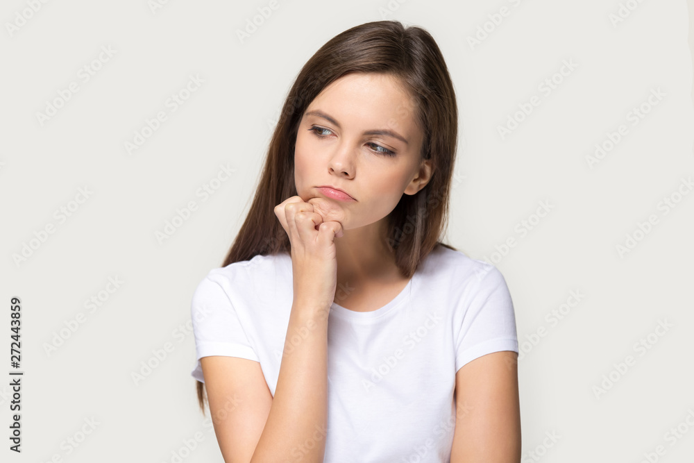 Millennial sad pensive woman feels upset isolated on grey background Millennial sad pensive woman feels upset isolated on grey background