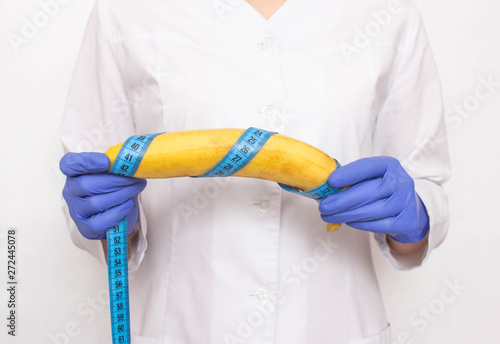 Doctor holds banana in hand with measuring tape. Concept of increasing male penis and operation, increase male organ