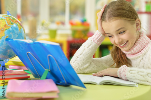 Cute girl leaning on hand while doing her homework