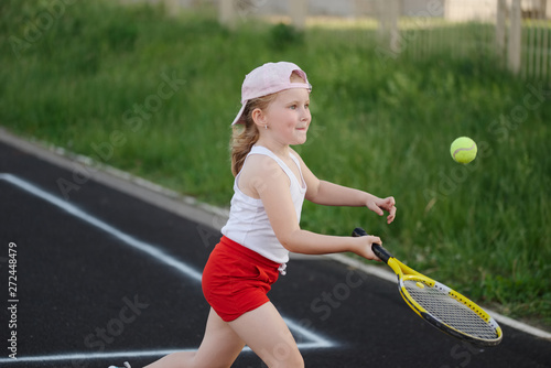happy girl plays tennis on court outdoors © Aliaksei Lasevich