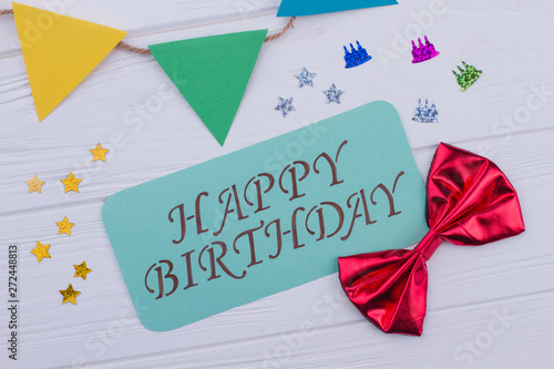 Happy Birthday card and coloful accessories. Birthday party decorations and card with inscription Happy Birthday on wooden background.