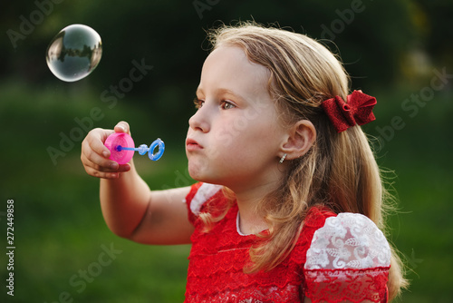 little girl with bubbles in summer park