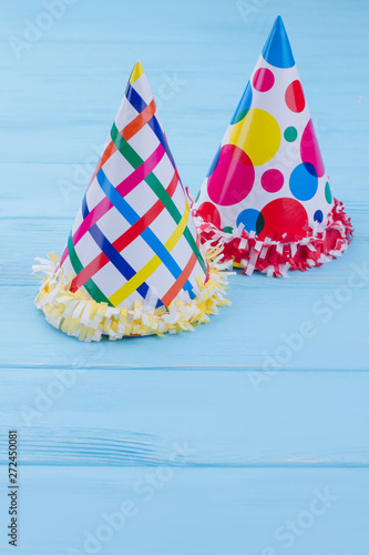 Birthday party hats for kids. Party cone caps on blue wooden background with text space.