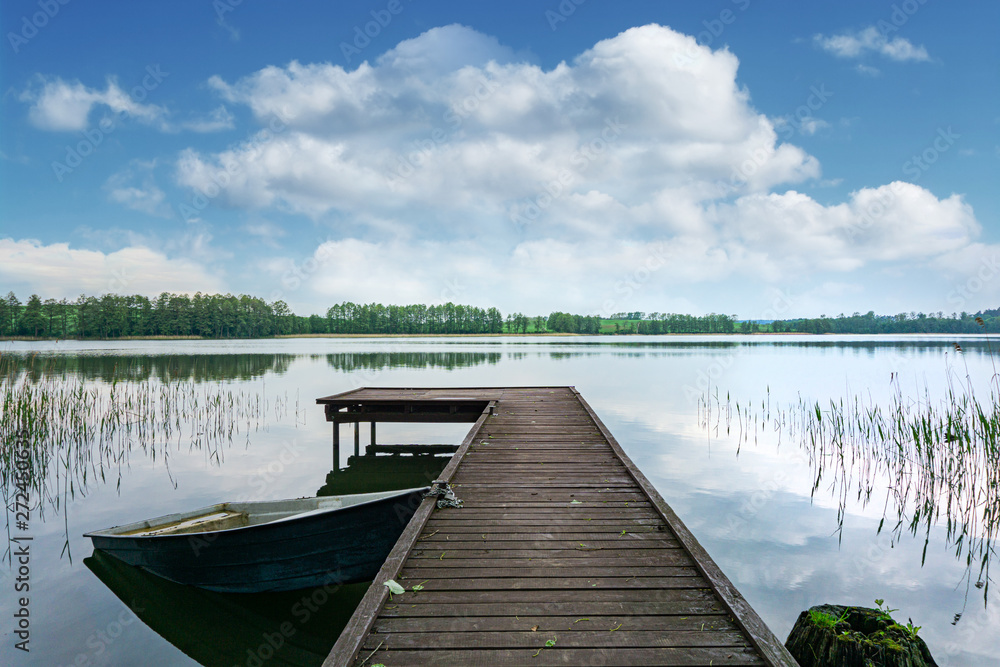 Beautiful view of the lake, wooden pier and boats. Spring, Mazury, Poland.