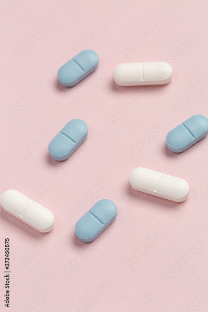 White and blue medical pills on a pink background White and blue medical pills on a pink background