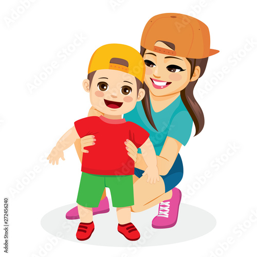 Mom holding toddler son helping child walk first baby steps