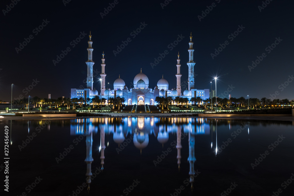 Iconic Islamic Site: Grand Mosque in Abu Dhabi, United Arab Emirates at night with a reflection in the pool showing off its beautiful colours of purple in the sky and water.