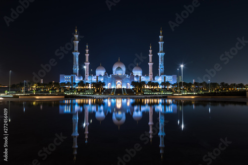 Iconic Islamic Site: Grand Mosque in Abu Dhabi, United Arab Emirates at night with a reflection in the pool showing off its beautiful colours of purple in the sky and water.