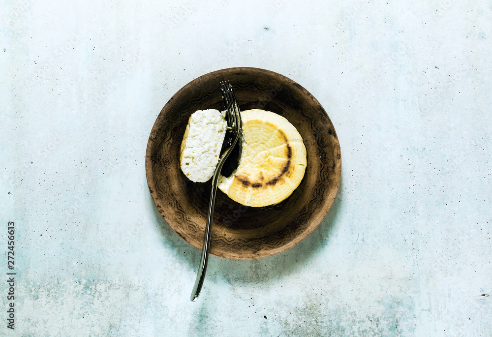 Oven baked ricotta cheese on a clay plate and fork. basic cooking techniques of Italian cuisine. breakfast. Oven baked ricotta cheese on a clay plate and fork. basic cooking techniques of Italian cuisine. breakfast.