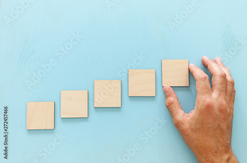 Hand arranging wood block stacking as chart or ladder. concept for growth and success © tomertu
