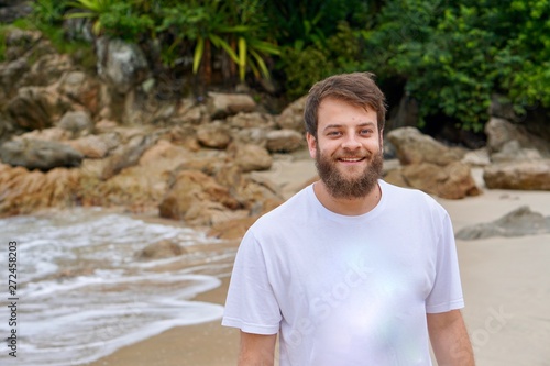 Close up portrait of a Brazilian man with blue eyes and a beard smiling on the beach