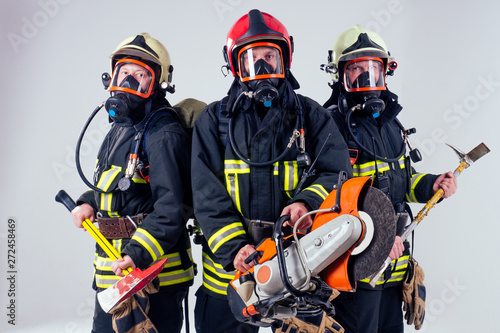 Portrait of three firefighters standing together white background studio