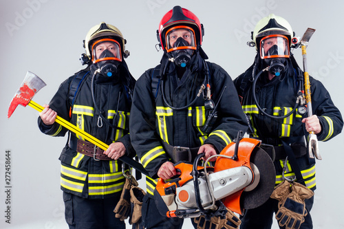 Portrait of three firefighters standing together white background studio