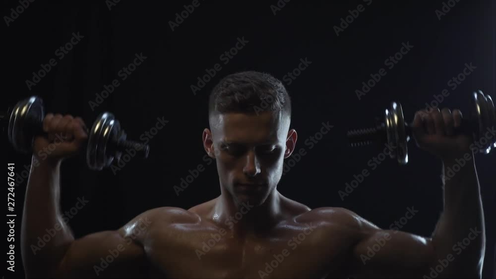 Young fit guy doing dumbbell press, silhouette, slow motion Young fit guy doing dumbbell press, silhouette, slow motion