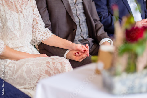 Wedding Scenery: Couple is attending the wedding ceremony while holding their hands - symbol of marriage and wedding.