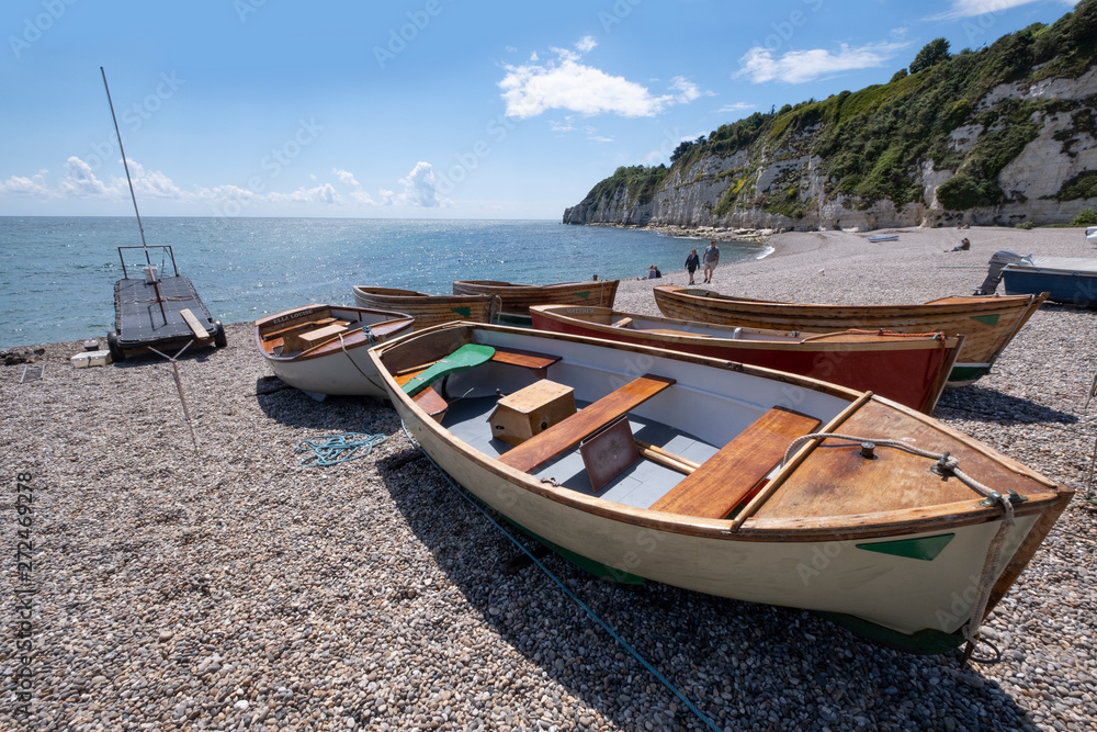 Devon seaside resort, wooden boats washed up on deserted shingle beach at Beer, South Devon, UK.
