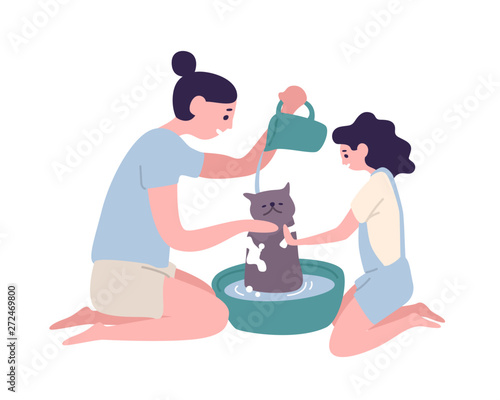 Happy mother and daughter washing cat at home