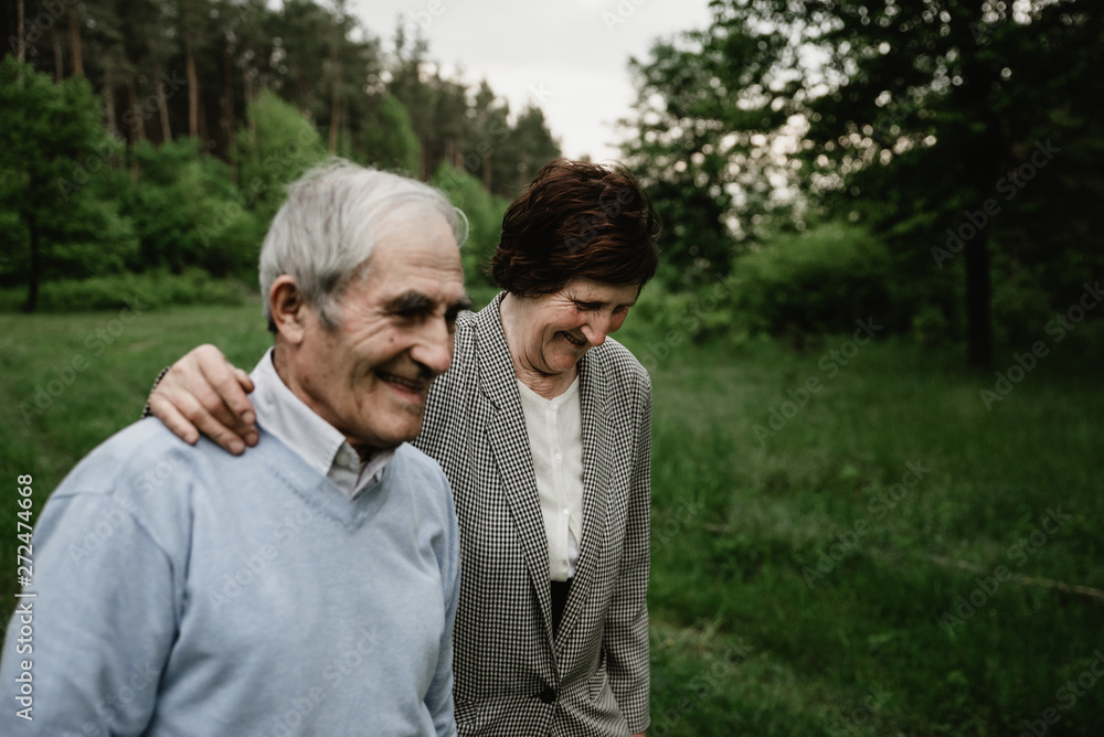 Happy smiling senior couple in love on nature, having fun. Elderly couple on the green field. Cute senior couple walking and hugging in spring forest Happy smiling senior couple in love on nature, having fun. Elderly couple on the green field. Cute senior couple walking and hugging in spring forest