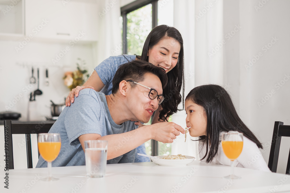 Asian family happy enjoy having breakfast on table in kitchen Asian family happy enjoy having breakfast on table in kitchen