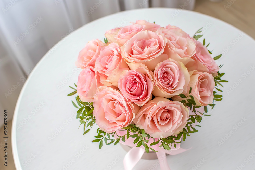 Beautiful bouquet of pink roses in a festive round box on a white table. Gift for holiday, birthday, Wedding, Mother's Day, Valentine's day, Women's Day. Flowers in a hat box. Top view. Beautiful bouquet of pink roses in a festive round box on a white table. Gift for holiday, birthday, Wedding, Mother's Day, Valentine's day, Women's Day. Flowers in a hat box. Top view.