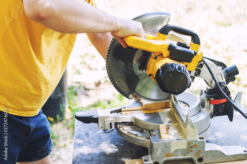 a man is cutting boards with a saw outdoor © stopabox