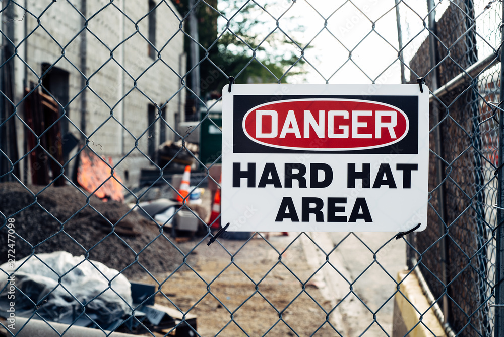 Hard Hat area warning sign on a fence at a construction site Hard Hat area warning sign on a fence at a construction site