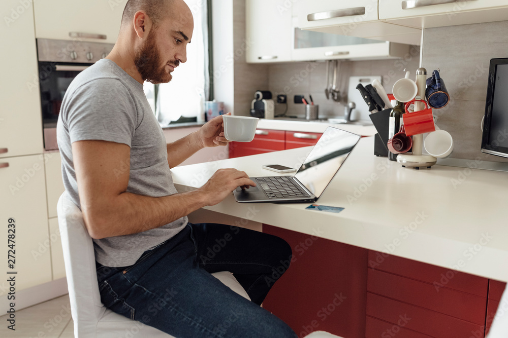 Adult Couple Using a Laptop From a Kitchen during the Morning Breakfast Adult Couple Using a Laptop From a Kitchen during the Morning Breakfast