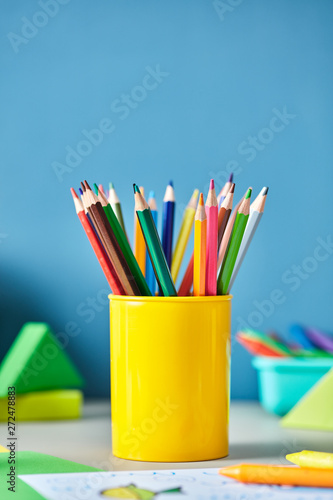 Colorful pencils in yellow cup on desk