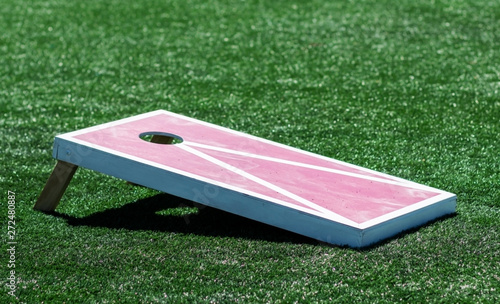 Side view of homemade cornhole game on turf field photo