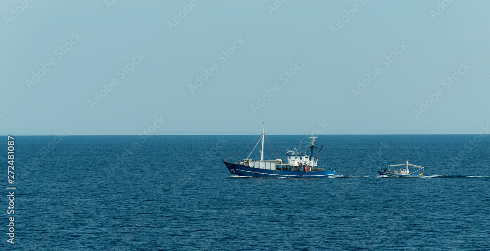 Small ship towing a boat in the sea