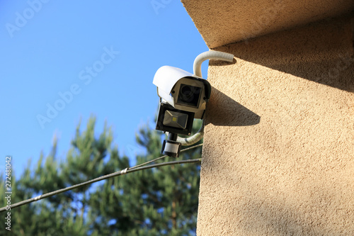 Kamera monitoringu z reflektorem led i czujnikiem ruchu na ścianie budynku.