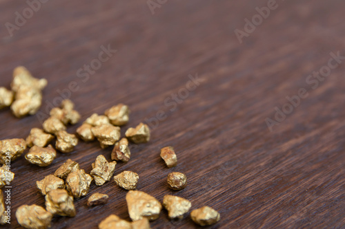 mound of gold nugget on dark wood background