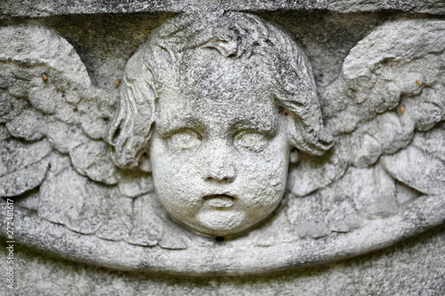 The weathered face of an angel. A damaged sandstone sculpture.