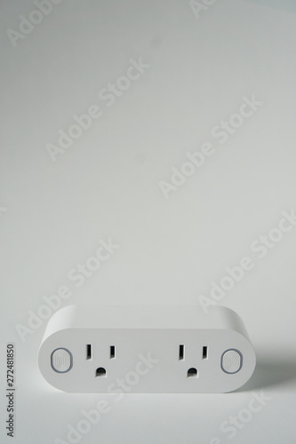 This double smart WIFI plug outlet can switch an electric device on or off via wi-fi. Isolated on a vertical white background with copyspace or empty room space for text or copy.