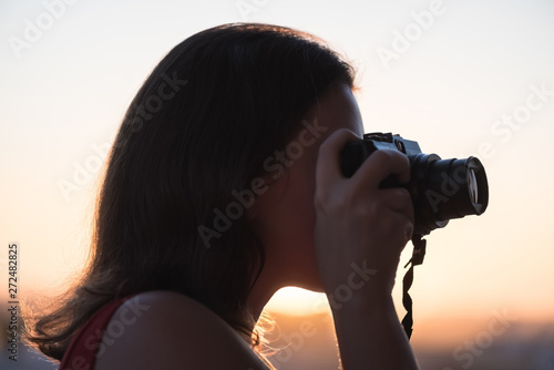 Silhouette of girl photographer taking picture on compact camera on the sunset background. photo