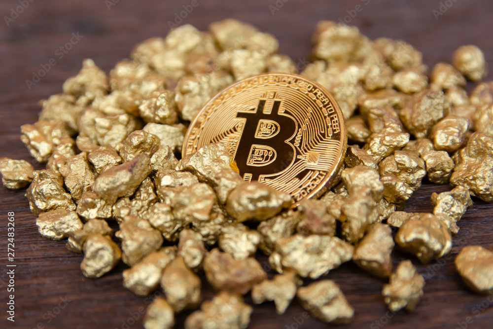 golden bitcoin on mound of gold nugget on dark wood background