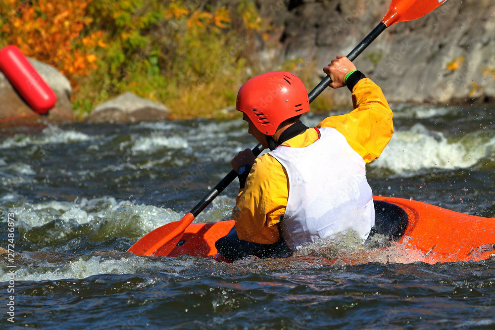 Fototapeta premium Whitewater kayaking on fast moving water of mountain river among the rapids, extreme water sport. Kayak freestyle on whitewater. Man in red kayak