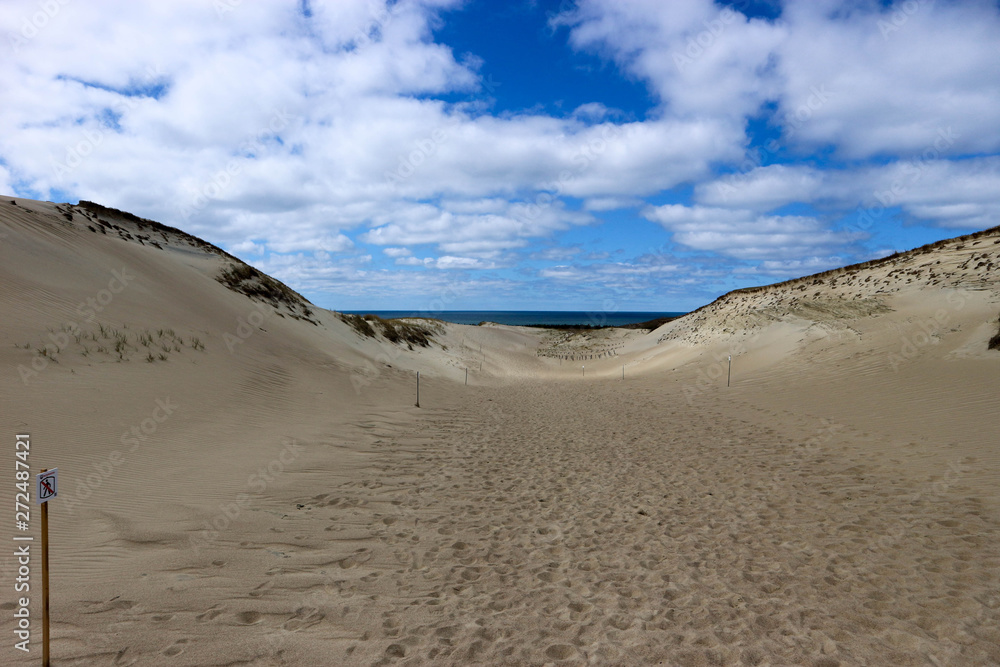 Beautiful endless sand dunes on the baltic sea coast under bright blue sky with clouds, Curonian Spit, Lithuania