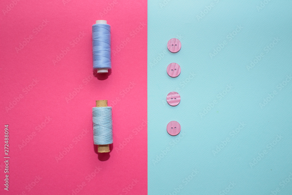 Composition with blue threads and sewing accessories on pink background. Pink buttons on blue background. Flatlay, place for text Composition with blue threads and sewing accessories on pink background. Pink buttons on blue background. Flatlay, place for text