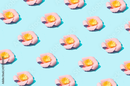 Trendy sunlight Summer pattern made with pink paper flower on bright light blue background. Minimal summer concept.