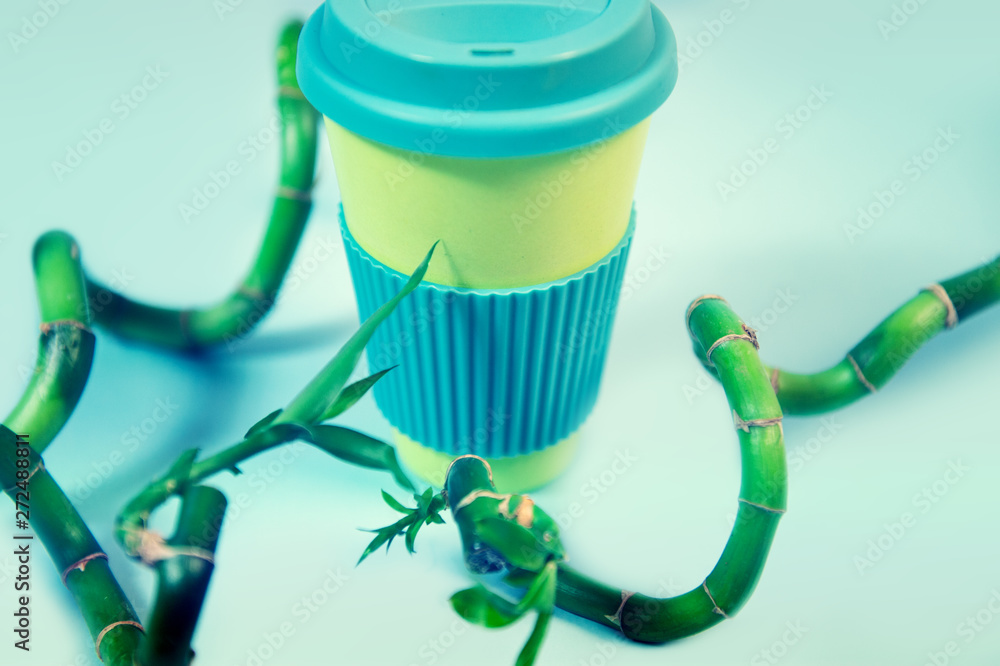 Zero waste concept. Stylish reusable eco coffee cup and green bamboo leaves. Zero waste concept. Stylish reusable eco coffee cup and green bamboo leaves.