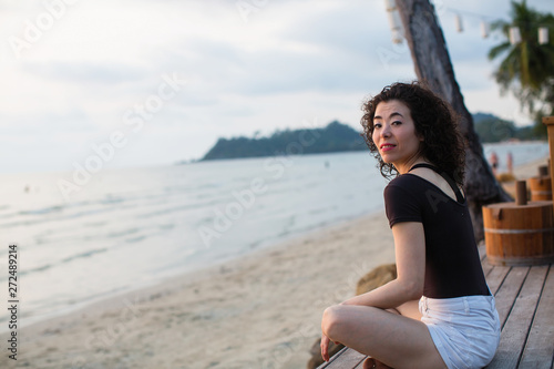 Asian woman sitting on the tropical sea beach.
